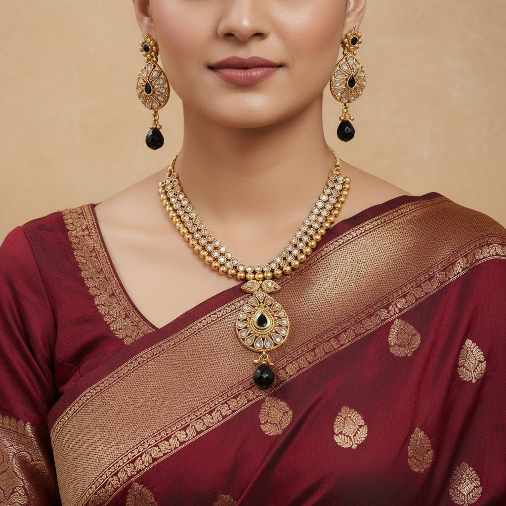 Gold necklace with black beads on a patterned surface