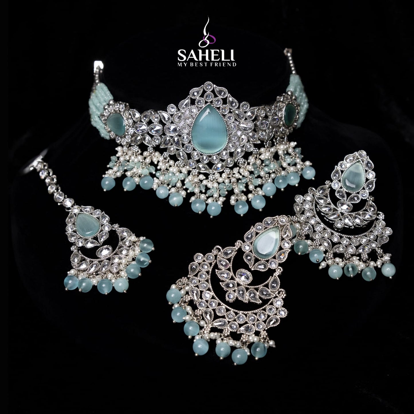 Jewelry set with blue stones and silver accents on a black background, featuring the brand 'Saheli'.