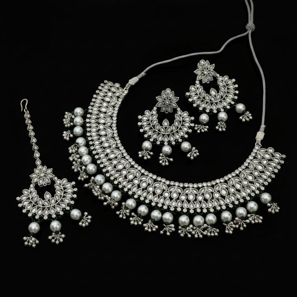 Silver jewelry set including necklace, earrings, and tikka on a dark background