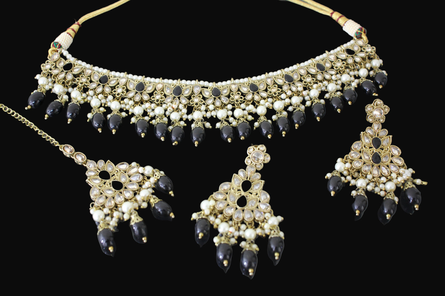 Ornate necklace and earrings set with black and white stones on a dark background