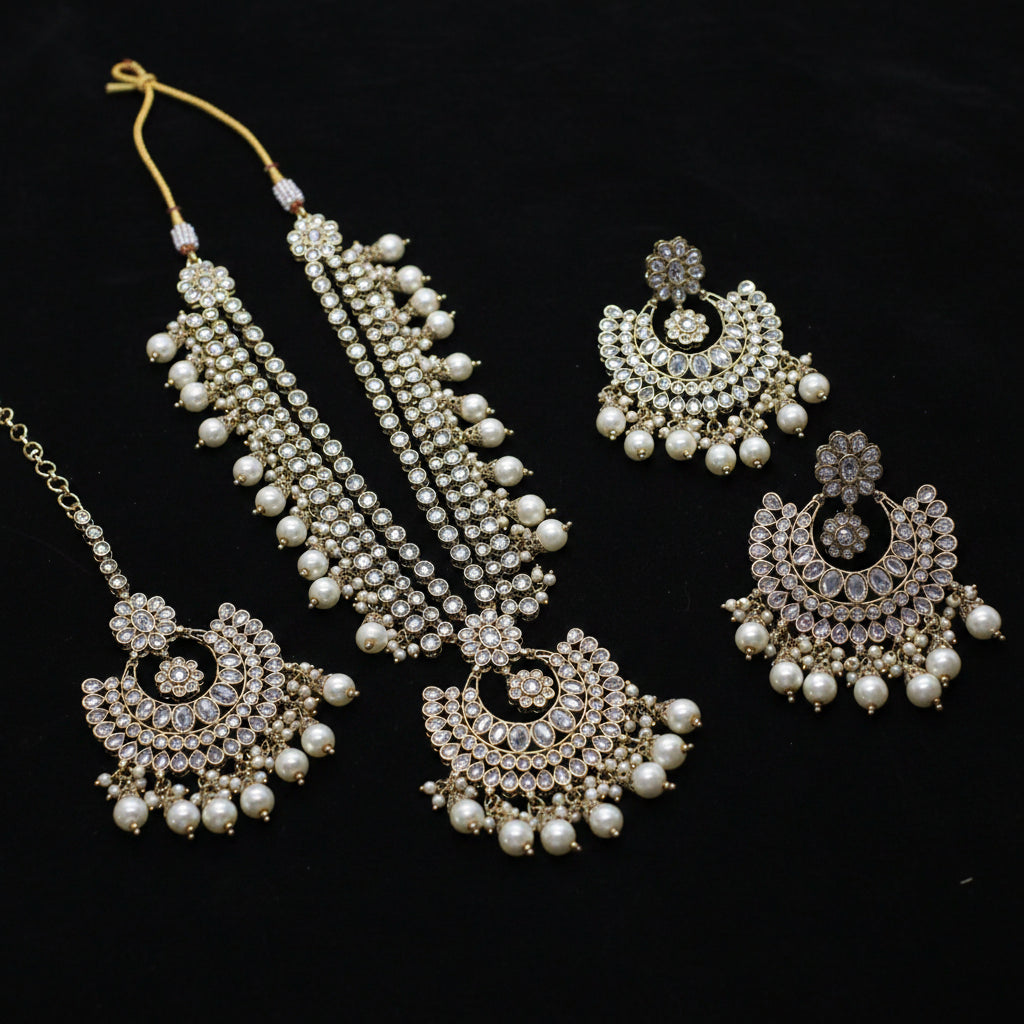 Ornate necklace and earrings with pearls and crystals on a dark background