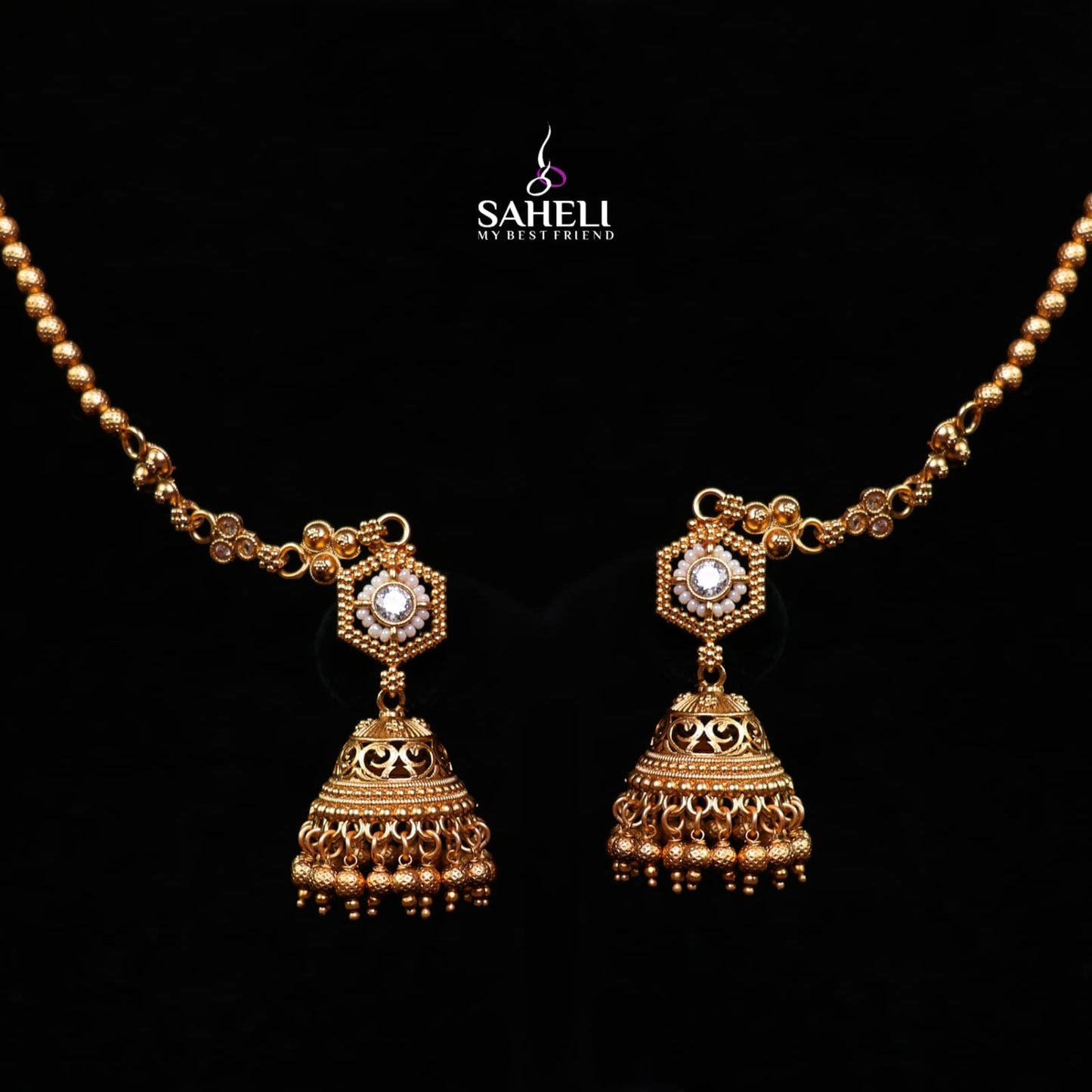 Gold necklace and earrings set with intricate designs on a black background, featuring the brand 'Saheli'.