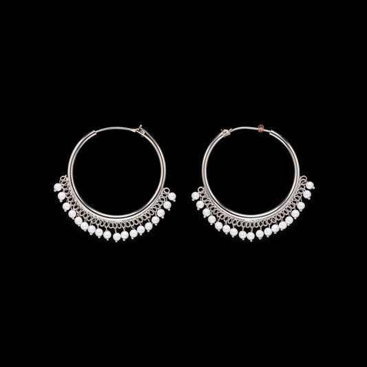 Pair of silver hoop earrings with bead detailing on a brown background