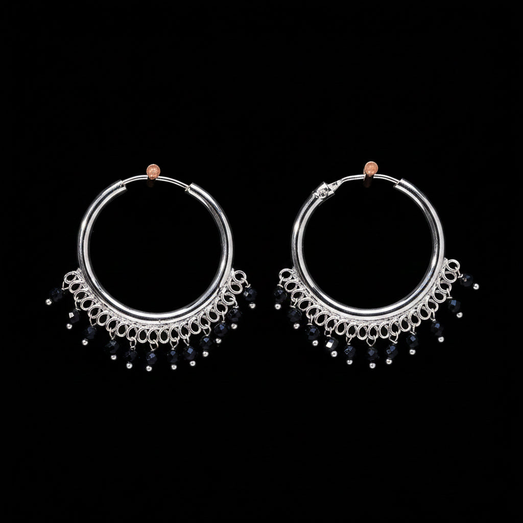 Pair of silver hoop earrings with black beads on a brown textured background