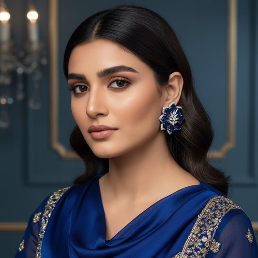 Pair of floral earrings with blue and silver design on a pink background
