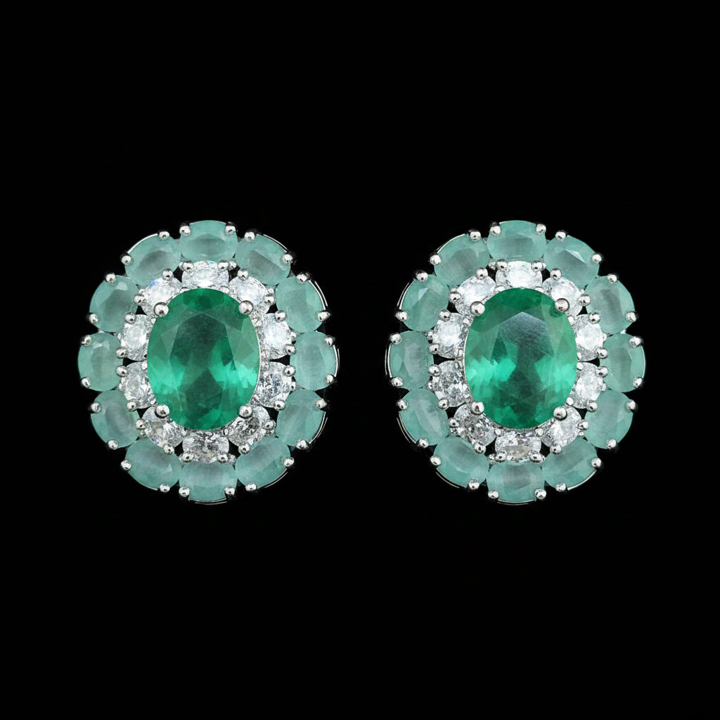 Pair of green gemstone earrings with silver accents on a red background