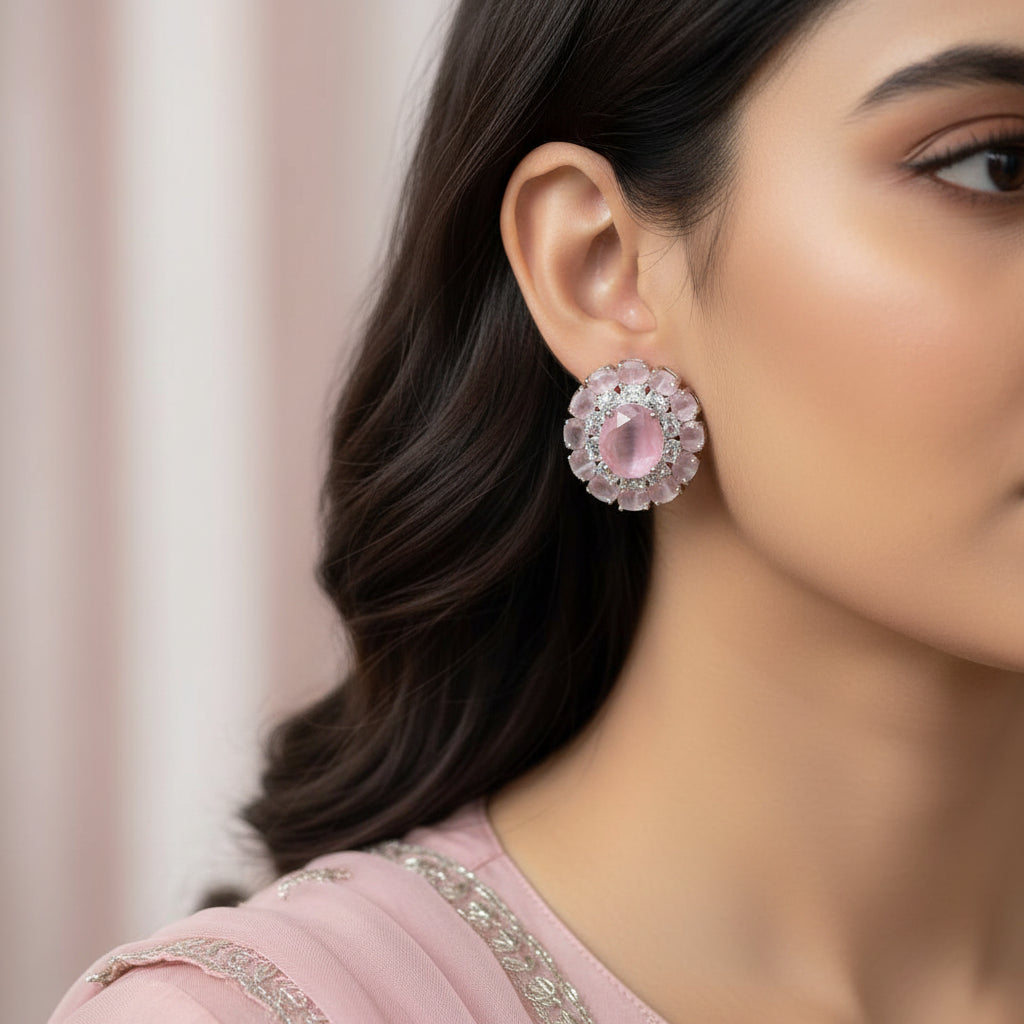 Pair of earrings with pink stones and silver accents on a red background