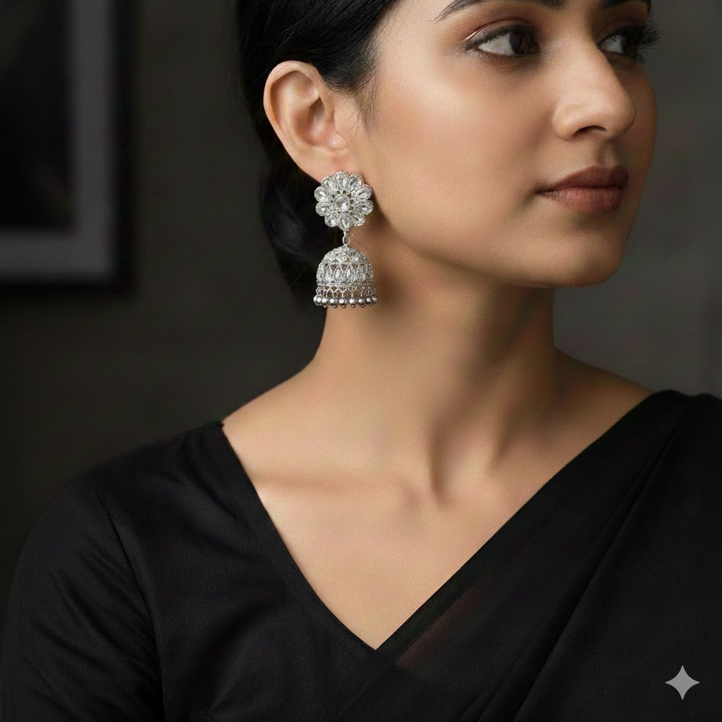 Woman wearing a black saree with a large, ornate earring on a dark background