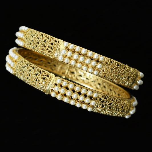 Gold and pearl bangles on a black stand with 'Saheli' branding.