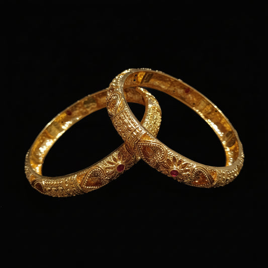 Two gold bangles with intricate designs on a light gray background.