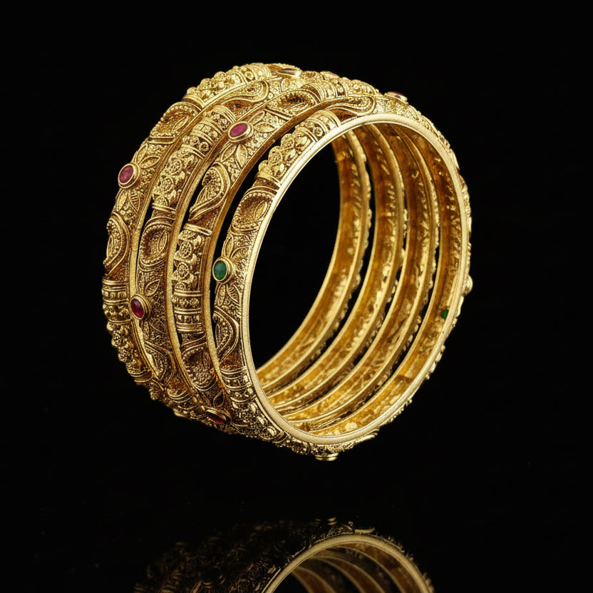 Set of gold bangles with embedded stones on a gray background, featuring the brand 'Saheili'.