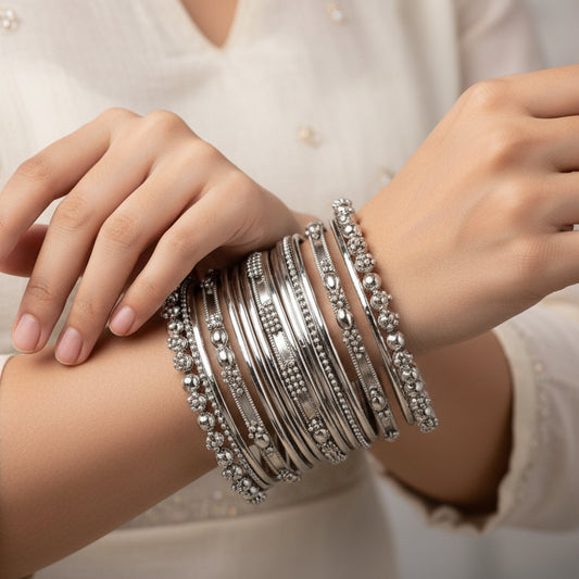 Stack of silver bangles with intricate designs on a white background