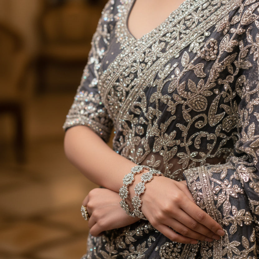 Silver floral bracelet on a gray cushion against a dark background