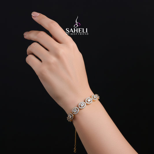 Gold bracelet with clear stones on a black background, featuring the 'Saheli' brand.