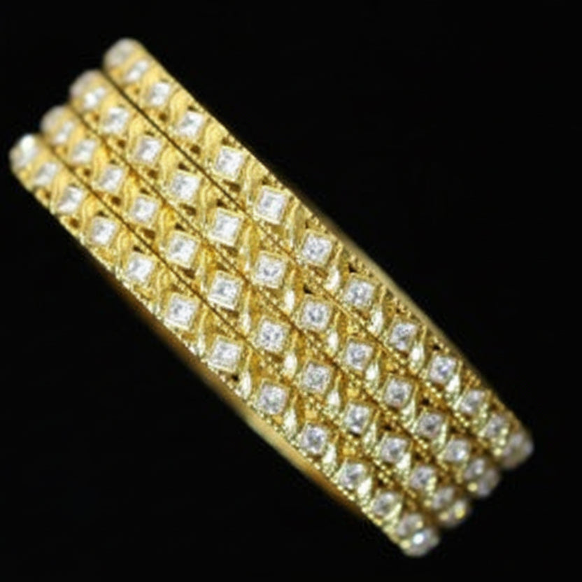 Gold bracelet with clear stones on a black cushion, branded 'Saheli'.