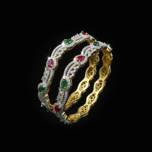 Gold bracelet with red and green stones on a black stand, branded 'Saheli'.