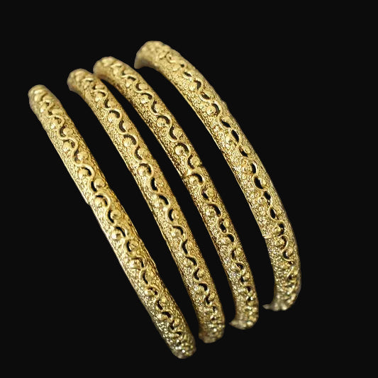 Gold bangles on a gray surface with 'SAHELI' branding.