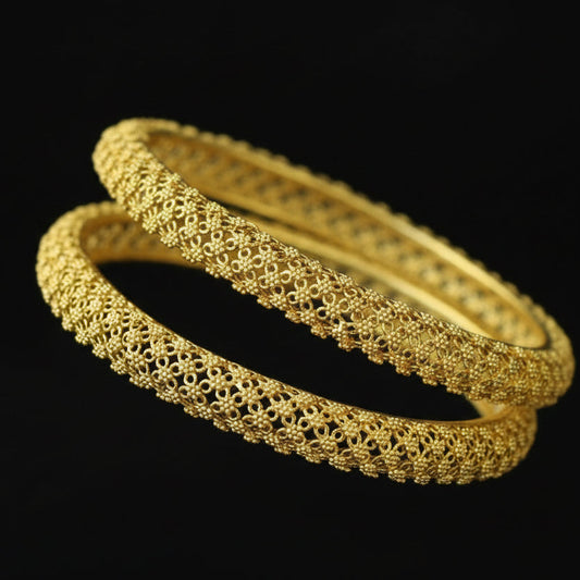 Gold bangles on a black velvet stand with 'SAHELLI' branding.