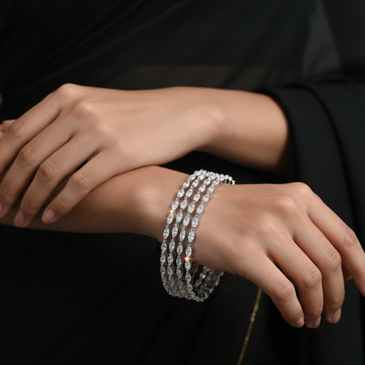 Set of diamond bracelets on a gray cushion against a dark background