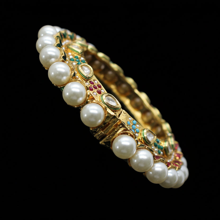 Jewelry bracelet with pearls and gemstones on a gray cushion