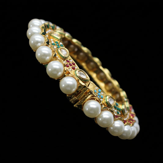 Jewelry bracelet with pearls and gemstones on a gray cushion