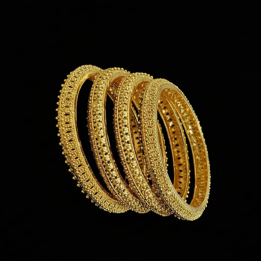 Set of gold bangles on a black stand against a gray background