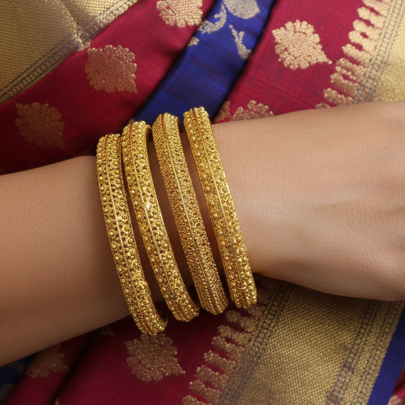 Set of gold bangles on a black stand against a gray background