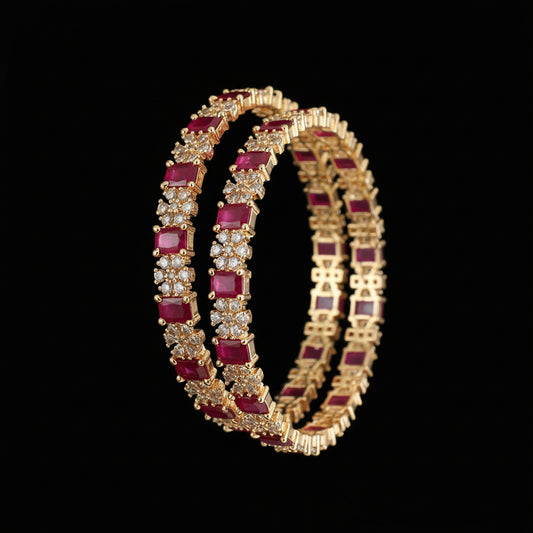 Gold bangles with red gemstones on a dark background