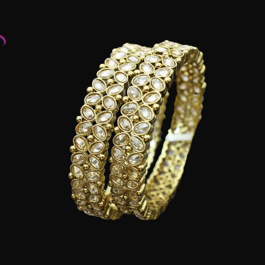 Gold bracelet with intricate design on a gray background, featuring the brand 'SAHELLI'.