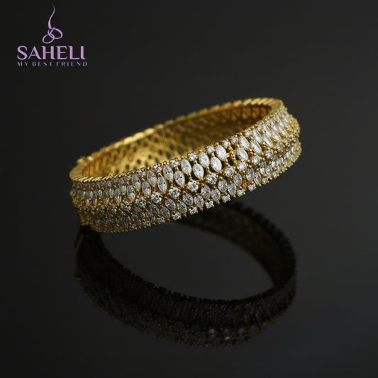 Gold bracelet with diamonds on a black background, featuring the brand 'Saheli'.