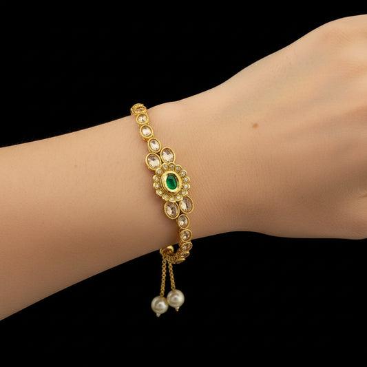 Gold bracelet with green gemstone and pearls on a dark background, branded 'SAHELI'.