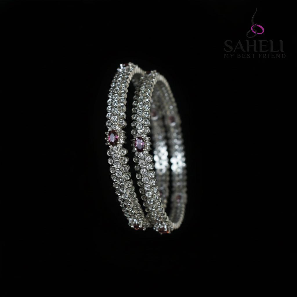 Silver bangles with purple stones on a black stand, branded 'Saheli'.