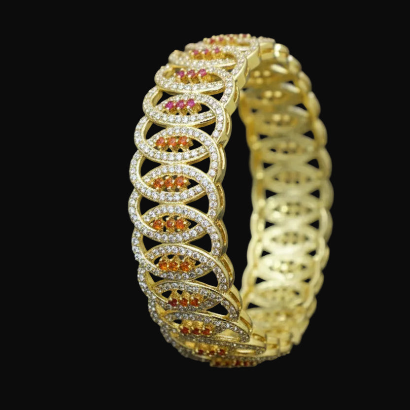 Gold bracelet with pink stones on a dark background, featuring the brand 'Saheli'.