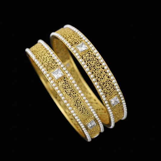 Gold bangles with diamond accents on a gray stand, branded 'SAHELI'.