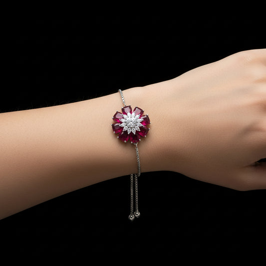 Silver bracelet with red and white gemstones on a gray background, branded 'SAHELLI'.