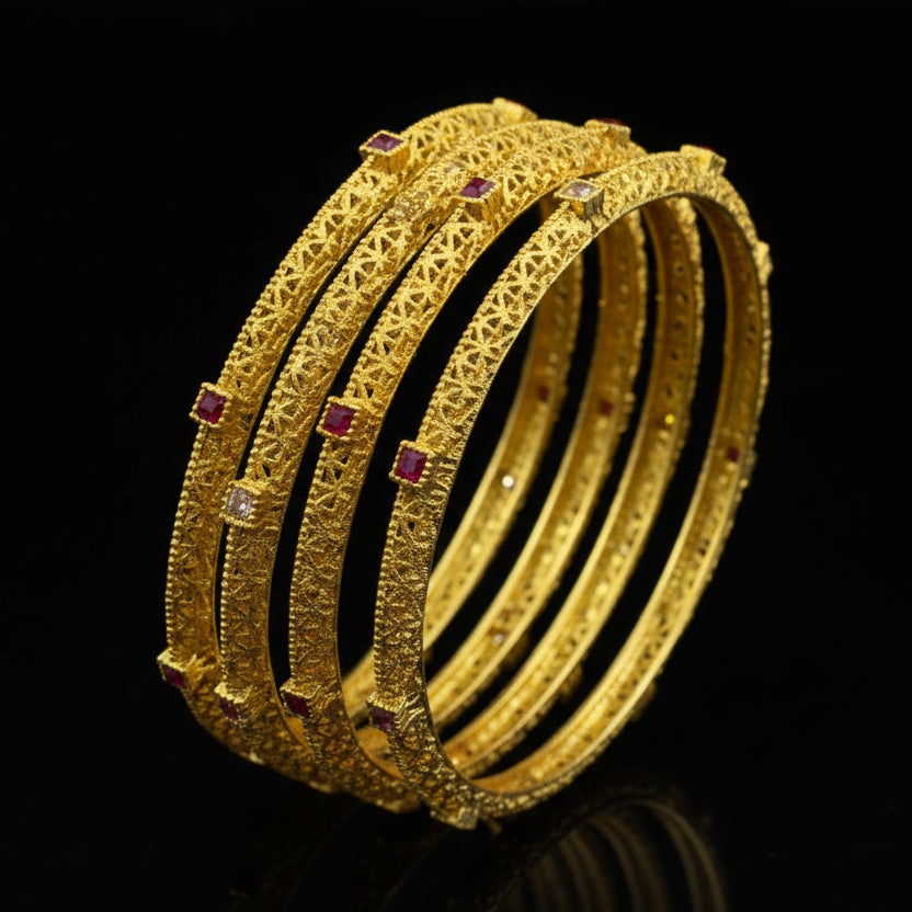 Gold bangles with red stones on a black stand, branded 'Saheli'.
