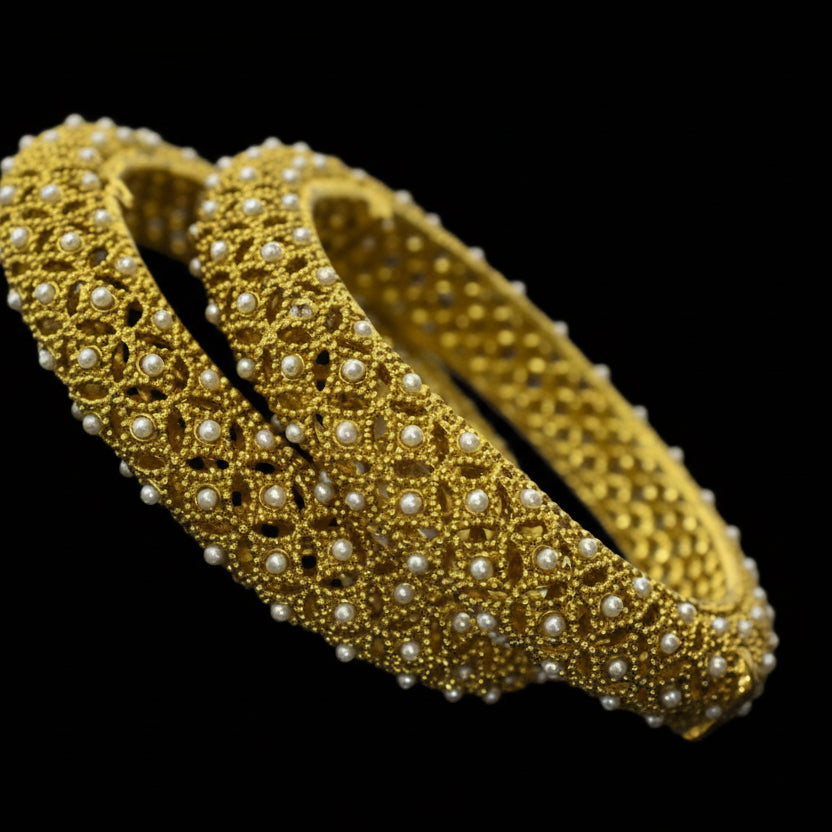 Gold bracelet with pearls on a reflective surface, branded 'Saheli'.