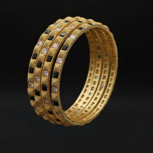 Gold bangles with gemstones on a textured surface