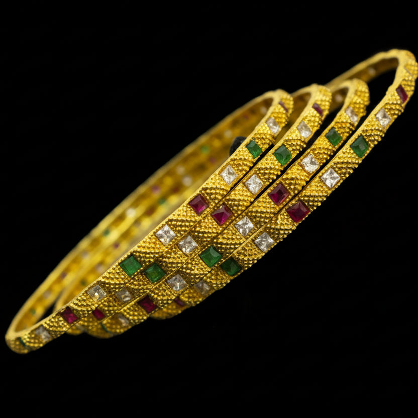 Gold bracelet with gemstones on a black background, featuring the brand 'SAHELI'.