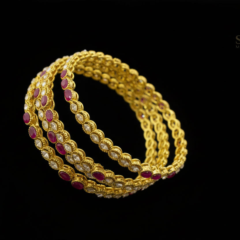 Gold bangles with red stones on a black stand, branded 'Saheli'.