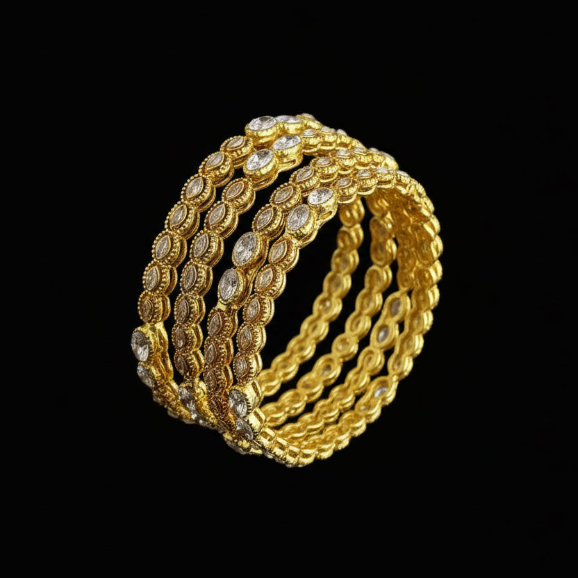 Gold bangles with embedded stones on a dark background, featuring the brand 'SAHELI'.