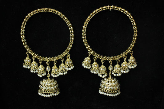 Pair of gold hoop earrings with dangling beads on a black background
