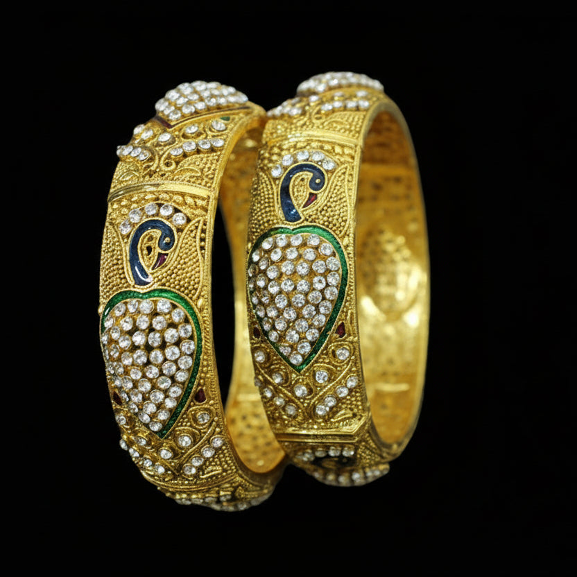 Gold bangles with intricate designs on a dark background, featuring the brand 'Saheli'.