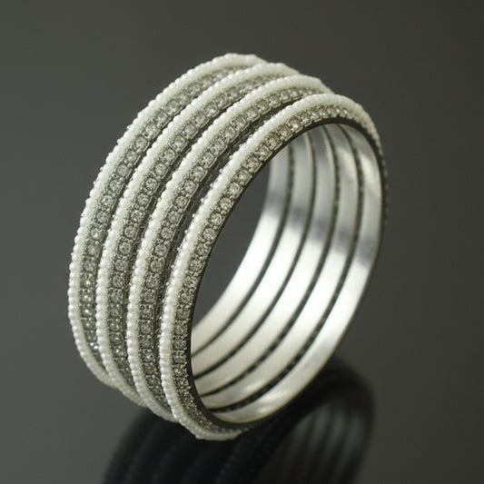 Set of silver bangles on a gray cushion against a dark background