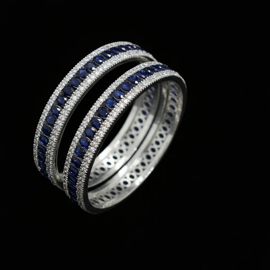 Two silver rings with blue gemstones on a dark gray background