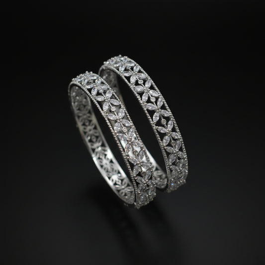 Two diamond bracelets on a gray cushion against a dark background