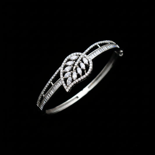 Silver leaf-shaped bracelet on a gray cushion with a dark background