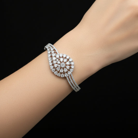Silver bracelet with intricate design on a gray cushion against a dark background