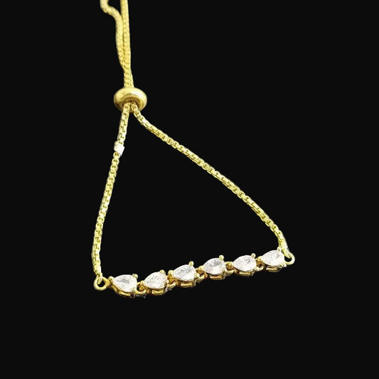 Gold bracelet with clear stones on a dark background, featuring the brand 'SAHELI'.