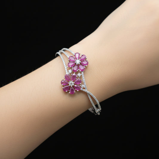Silver bracelet with pink gemstone flowers on a gray surface